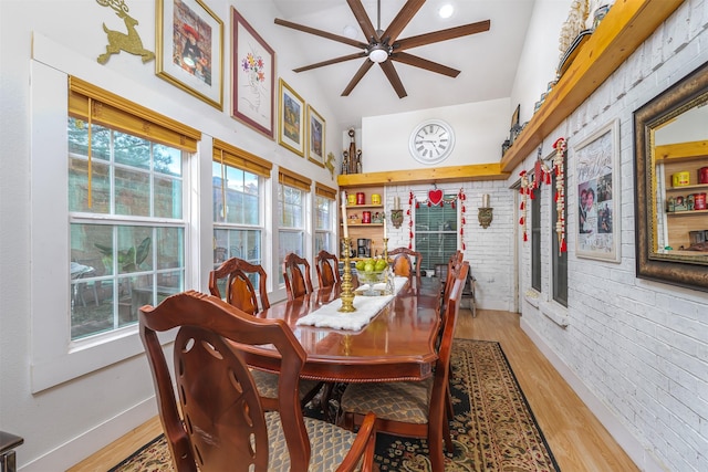 dining room featuring ceiling fan, hardwood / wood-style flooring, a high ceiling, and brick wall