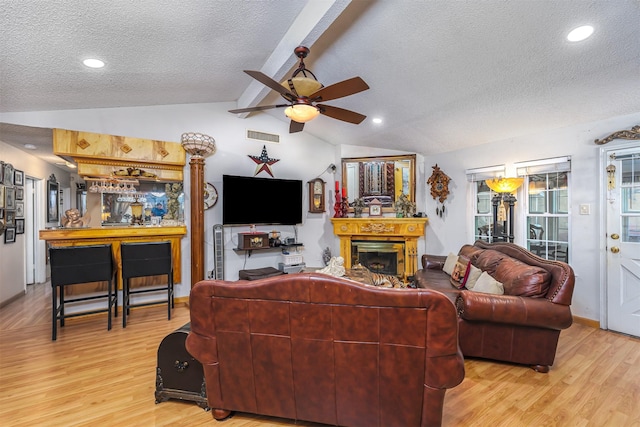 living room featuring lofted ceiling with beams, ceiling fan, a textured ceiling, and light hardwood / wood-style floors