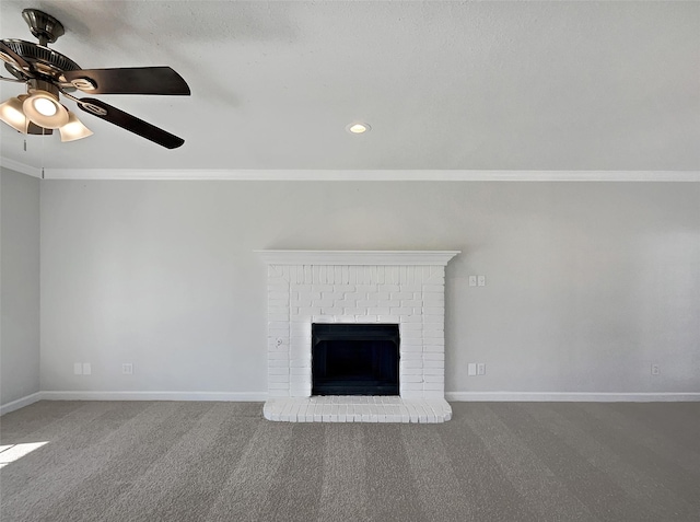 unfurnished living room with crown molding, ceiling fan, carpet flooring, and a brick fireplace