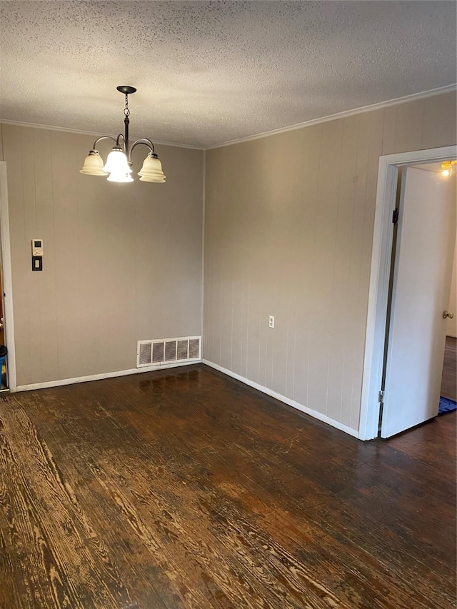 unfurnished room with ornamental molding, dark hardwood / wood-style floors, a notable chandelier, and a textured ceiling