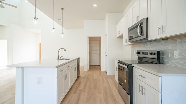 kitchen with appliances with stainless steel finishes, hanging light fixtures, and white cabinets