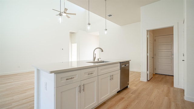 kitchen featuring sink, white cabinetry, hanging light fixtures, stainless steel dishwasher, and an island with sink