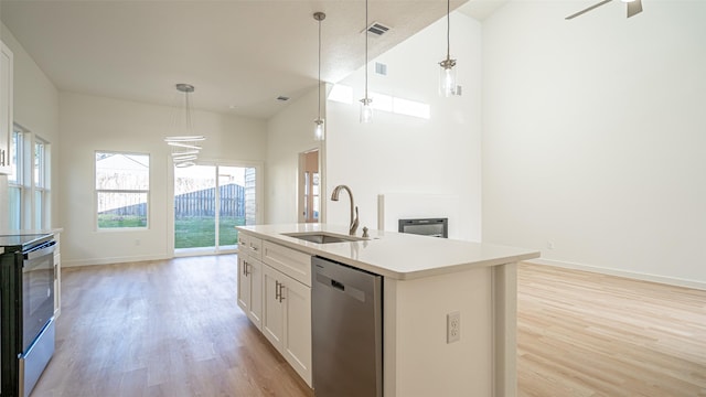 kitchen with a kitchen island with sink, sink, decorative light fixtures, and stainless steel appliances