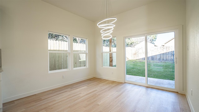 unfurnished dining area featuring an inviting chandelier and light hardwood / wood-style flooring