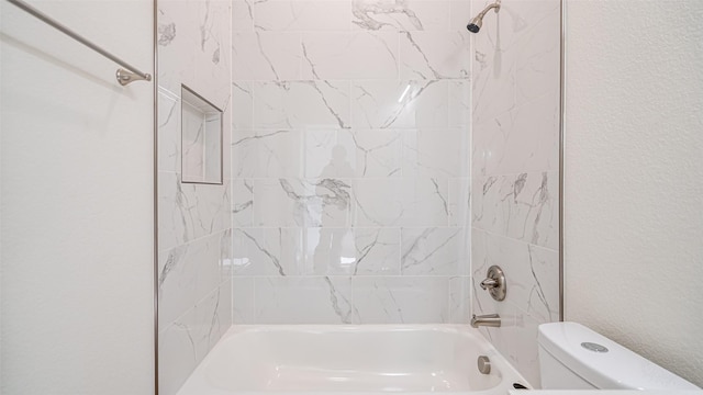 bathroom featuring toilet and tiled shower / bath