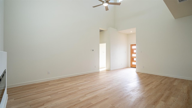 unfurnished living room featuring a towering ceiling, light hardwood / wood-style flooring, and ceiling fan