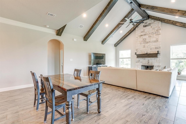 dining area featuring ceiling fan, a healthy amount of sunlight, a stone fireplace, and light hardwood / wood-style flooring