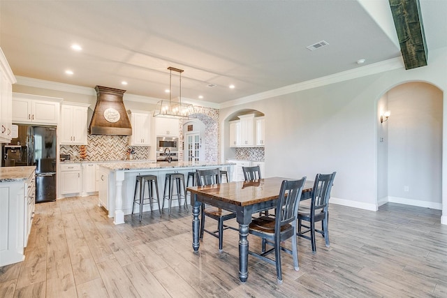 dining area featuring crown molding and light hardwood / wood-style flooring