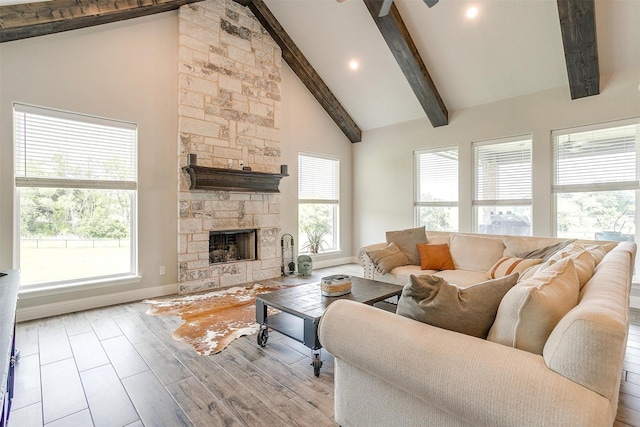 living room featuring a stone fireplace, high vaulted ceiling, light hardwood / wood-style floors, and beamed ceiling