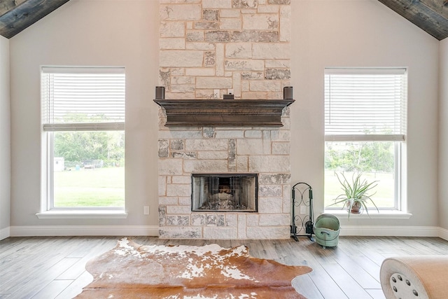 living room featuring vaulted ceiling, a stone fireplace, and light hardwood / wood-style floors