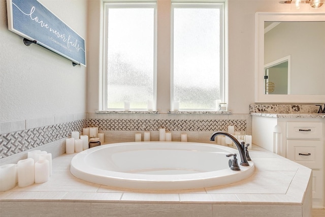 bathroom featuring vanity and tiled tub