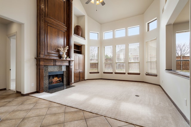 unfurnished living room with ceiling fan, high vaulted ceiling, light colored carpet, and a fireplace