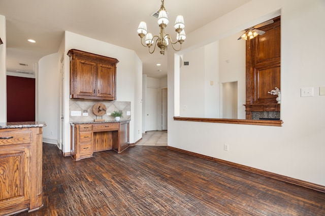 kitchen with a chandelier, dark stone countertops, dark hardwood / wood-style floors, pendant lighting, and backsplash