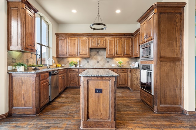 kitchen featuring dark hardwood / wood-style flooring, appliances with stainless steel finishes, a center island, and light stone counters