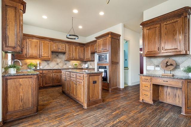 kitchen featuring sink, a center island, dark stone countertops, appliances with stainless steel finishes, and dark hardwood / wood-style floors