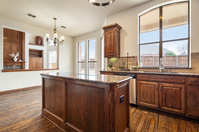 kitchen featuring sink, hanging light fixtures, dark hardwood / wood-style floors, a kitchen island, and stone counters