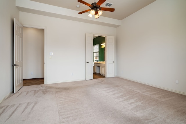 unfurnished bedroom with ceiling fan, light colored carpet, and ensuite bath