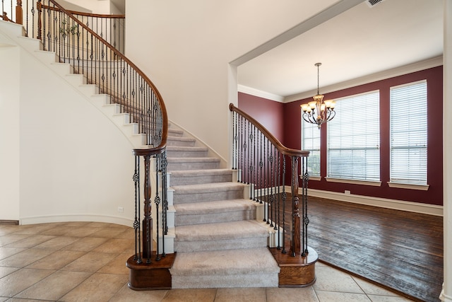 stairs with tile patterned flooring, crown molding, and an inviting chandelier