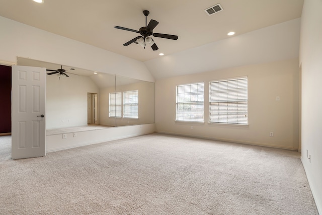 empty room featuring vaulted ceiling, light colored carpet, and ceiling fan