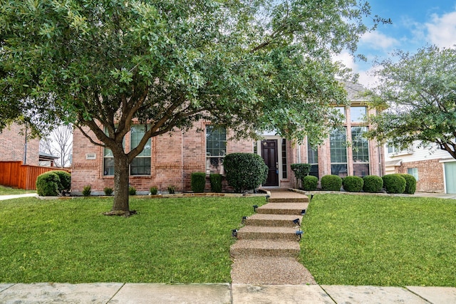 obstructed view of property with brick siding, a front lawn, and fence