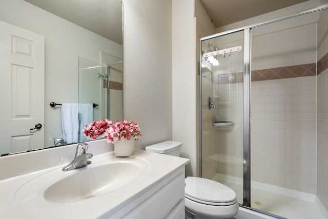 bathroom with vanity, a shower with shower door, and toilet