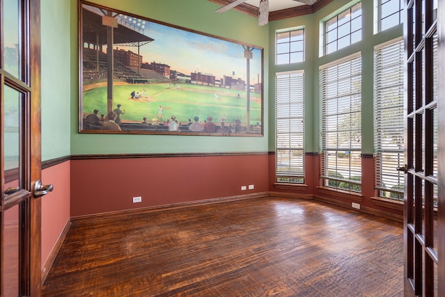 empty room with ceiling fan, ornamental molding, a wealth of natural light, and dark hardwood / wood-style flooring