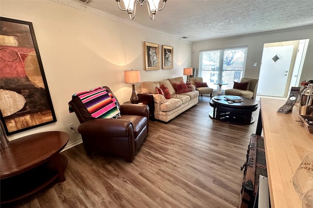 living room featuring an inviting chandelier, hardwood / wood-style flooring, ornamental molding, and a textured ceiling