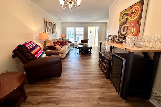 living room featuring ornamental molding, dark hardwood / wood-style floors, a textured ceiling, and a chandelier