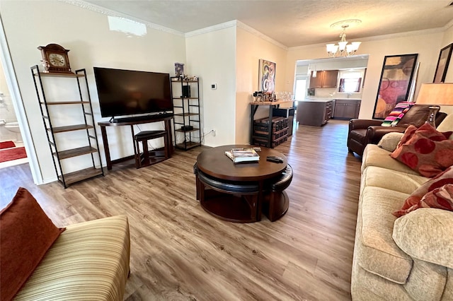 living room featuring hardwood / wood-style flooring, ornamental molding, and a chandelier