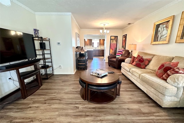 living room with crown molding, hardwood / wood-style floors, and a notable chandelier