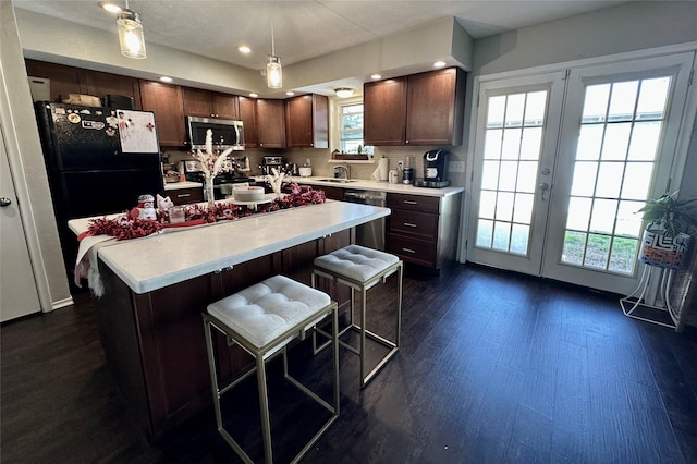 kitchen with french doors, a breakfast bar, decorative light fixtures, a center island, and appliances with stainless steel finishes