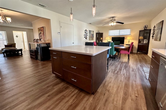 kitchen featuring dark hardwood / wood-style floors, dark brown cabinetry, decorative light fixtures, and a center island