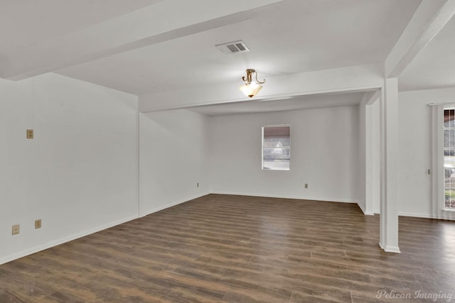 empty room featuring dark wood-type flooring, a wealth of natural light, and beam ceiling