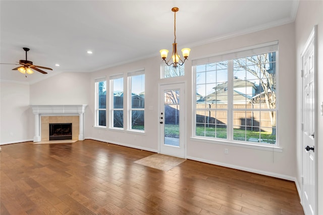 unfurnished living room featuring a tiled fireplace, crown molding, dark hardwood / wood-style floors, and a wealth of natural light