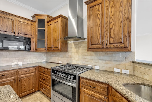 kitchen with backsplash, crown molding, light stone counters, gas range, and wall chimney range hood