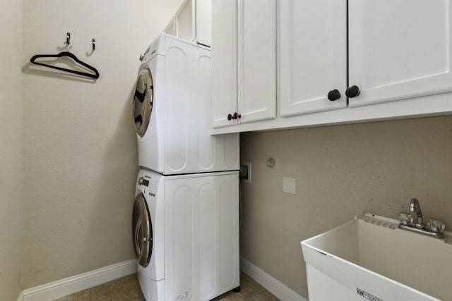 laundry room featuring cabinets, sink, and stacked washer / drying machine