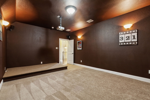 cinema room with light colored carpet and a textured ceiling