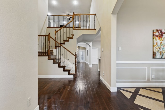 stairs with a towering ceiling and wood-type flooring