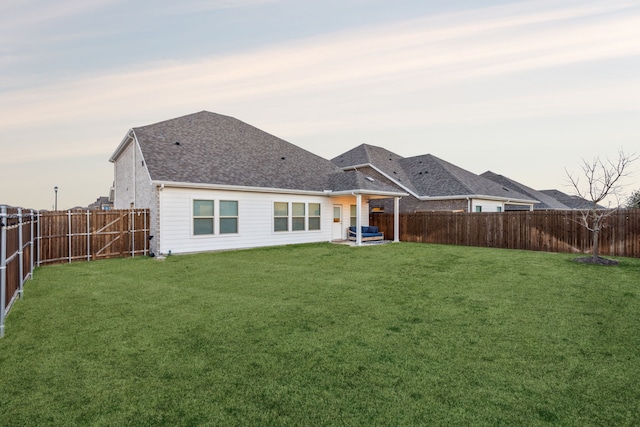 back house at dusk with a lawn