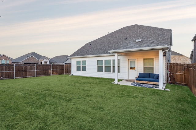 back house at dusk with a lawn and a patio