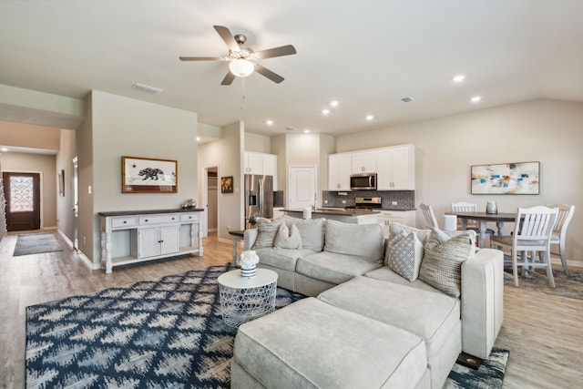 living room with lofted ceiling, light hardwood / wood-style flooring, and ceiling fan