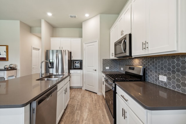 kitchen featuring white cabinetry, sink, stainless steel appliances, and a center island with sink