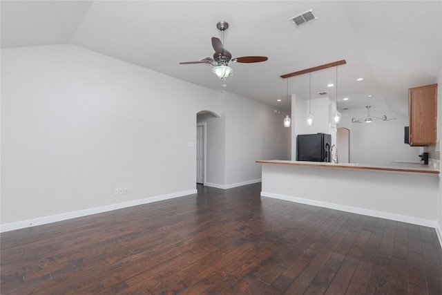 unfurnished living room with arched walkways, ceiling fan, visible vents, vaulted ceiling, and dark wood finished floors