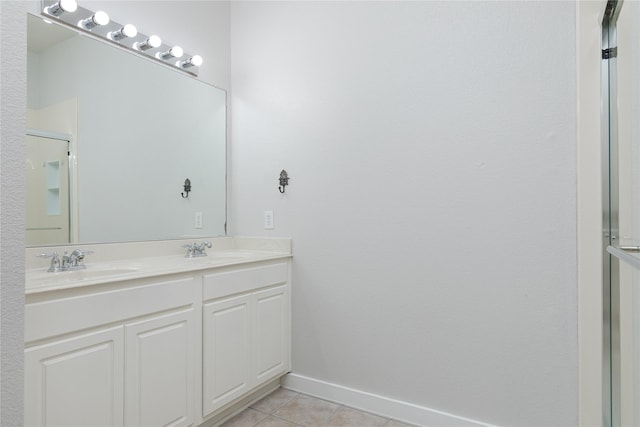 full bathroom with double vanity, a sink, baseboards, and tile patterned floors