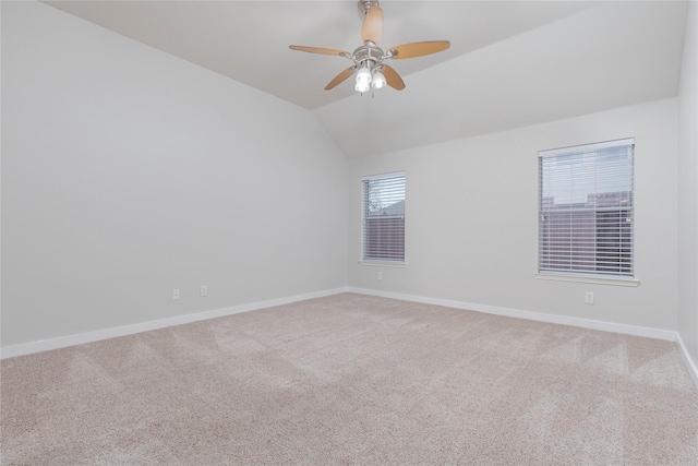 empty room featuring lofted ceiling, carpet flooring, a ceiling fan, and baseboards