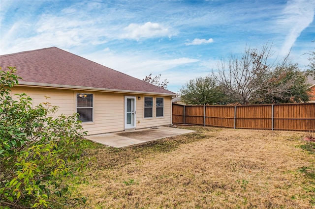 rear view of property with a shingled roof, fence, a patio, and a yard