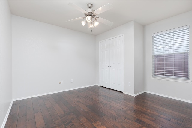 unfurnished bedroom with ceiling fan, a closet, dark wood finished floors, and baseboards