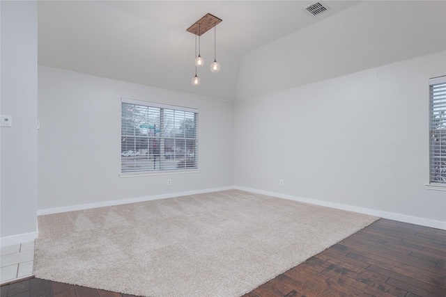 spare room featuring lofted ceiling, dark wood-style floors, baseboards, and visible vents