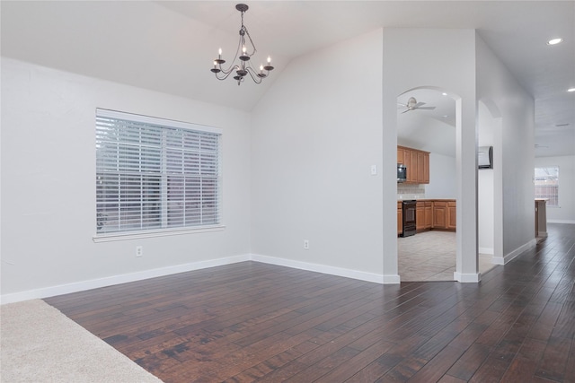 interior space featuring dark wood-type flooring, arched walkways, vaulted ceiling, and baseboards