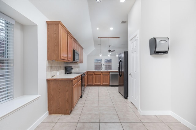 kitchen with light tile patterned floors, tasteful backsplash, brown cabinetry, light countertops, and black appliances